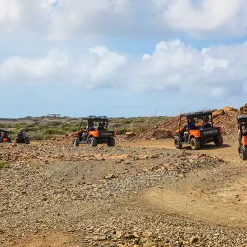 Tourists on a tour of Arikok National Park in Aruba, following dirt paths in four-wheel-drive buggies