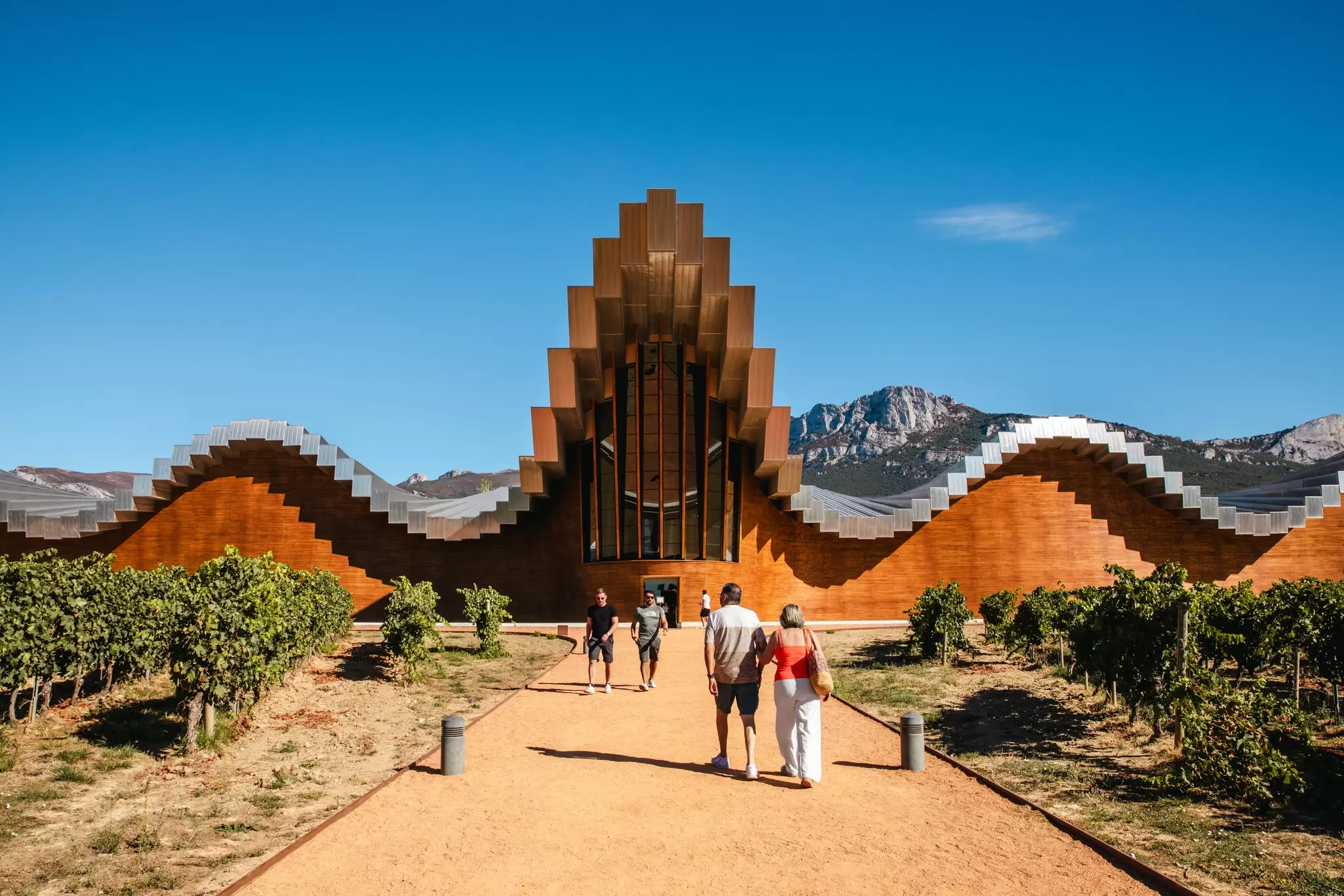 People enter a winery with an incredible undulating roof set in a mountain region: Bodegas Ysios, La Rioja, Spain