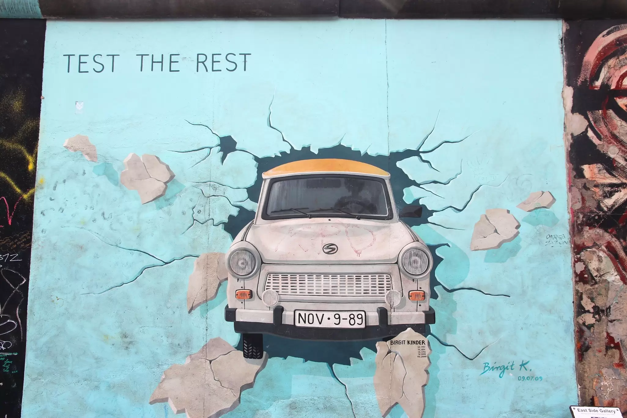 The Test The Rest artwork in the East Side Gallery, showing an old-fashioned car bursting through the wall.