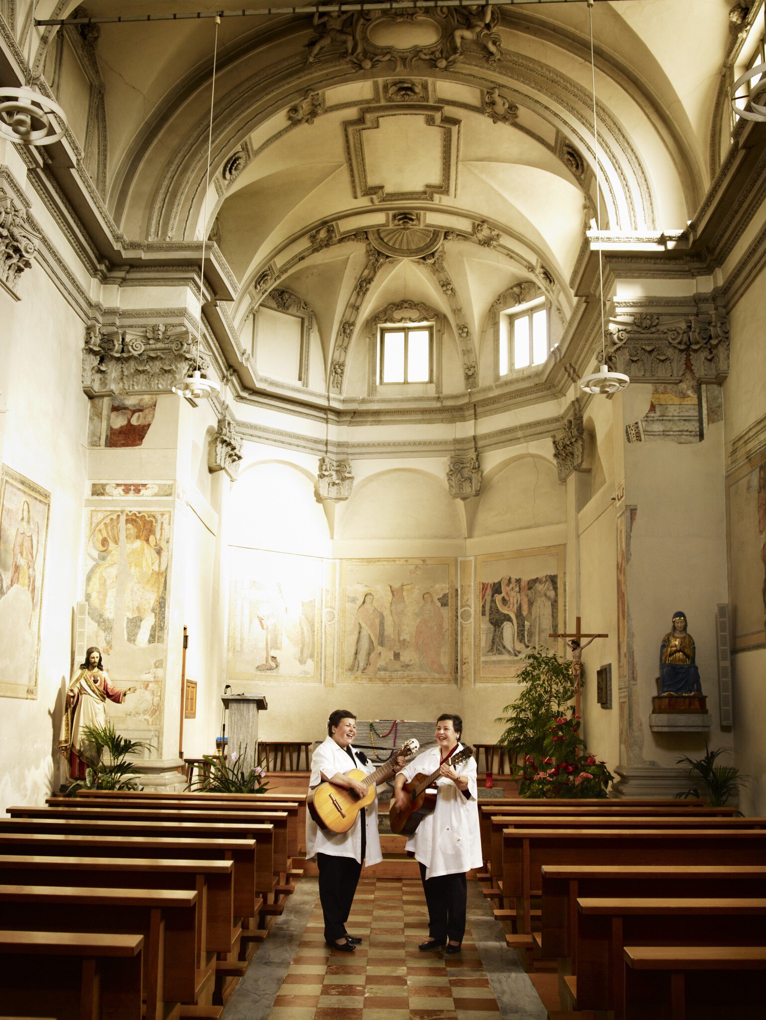 Two women singing and playing guitar in Bedigliora’s church.