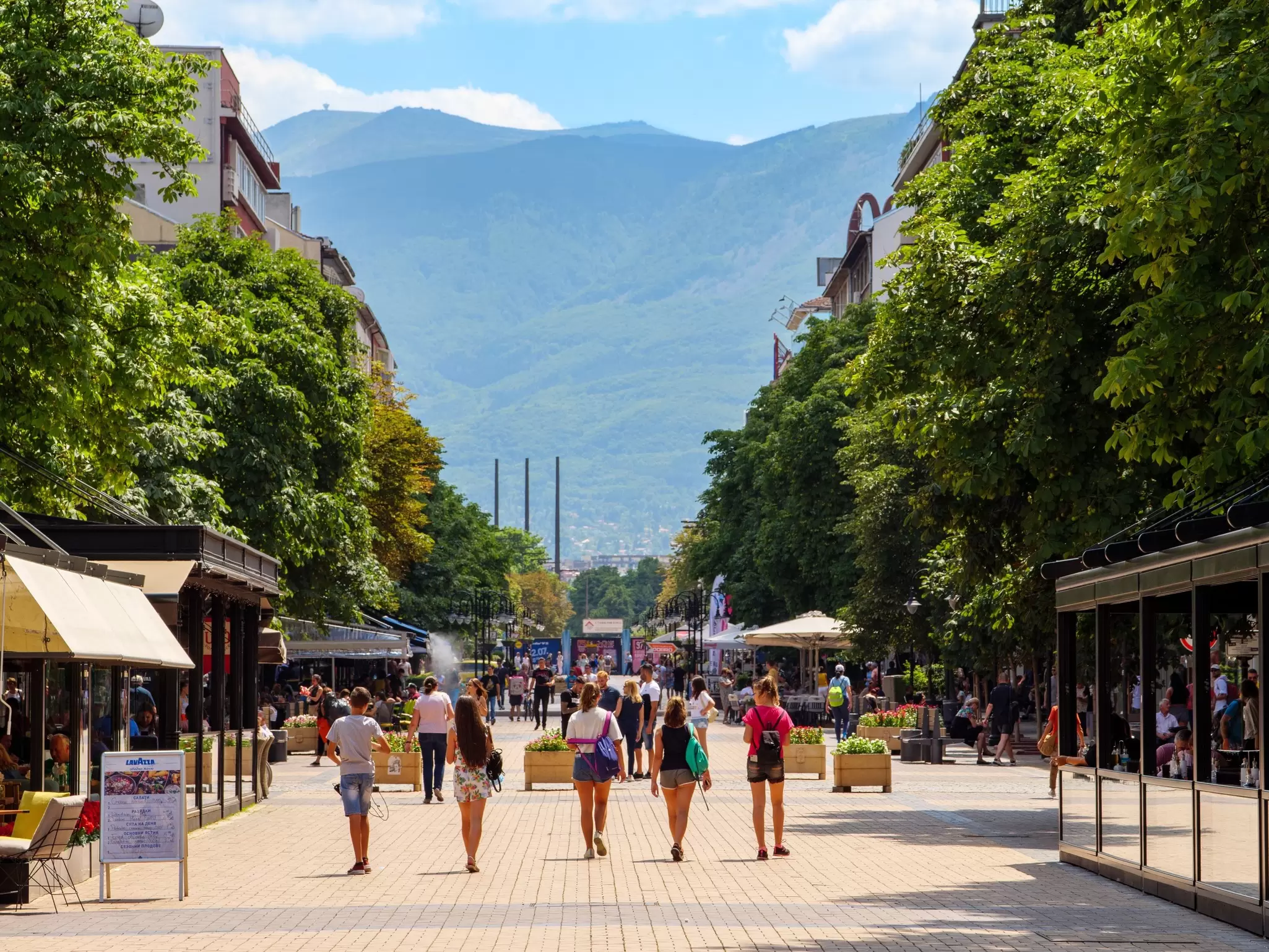 Mountains rise behind people walking on Vitosha Boulevard in Sofia, Bulgaria. 