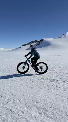 A woman rides a bike with thick tires through snow.