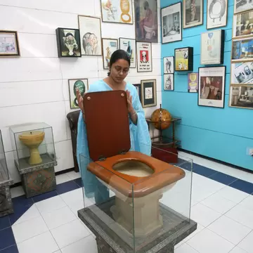 TO GO WITH STORY BY TRIPTI LAHIRI  An employee of the Sulabh International Museum of Toilets displays a Fancy Toilet used in the 1930s at the museum in New Delhi, 27 October 2007.   For India's low-cost toilet champion, each new loo means freedom ...