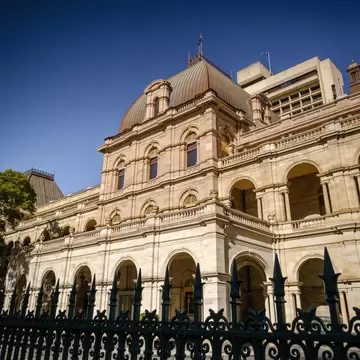 Exterior view of Queensland Parliament House with its sandstone facade and architectural columns. Brisbane, Australia.