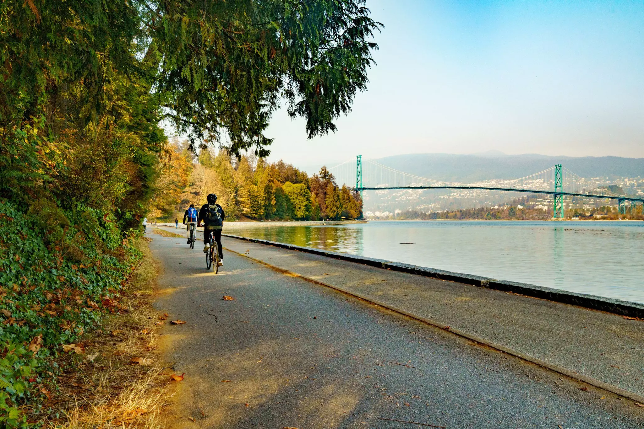 A beautiful shot of fall in Stanley park with people walking along the water in Vancouver, Canada