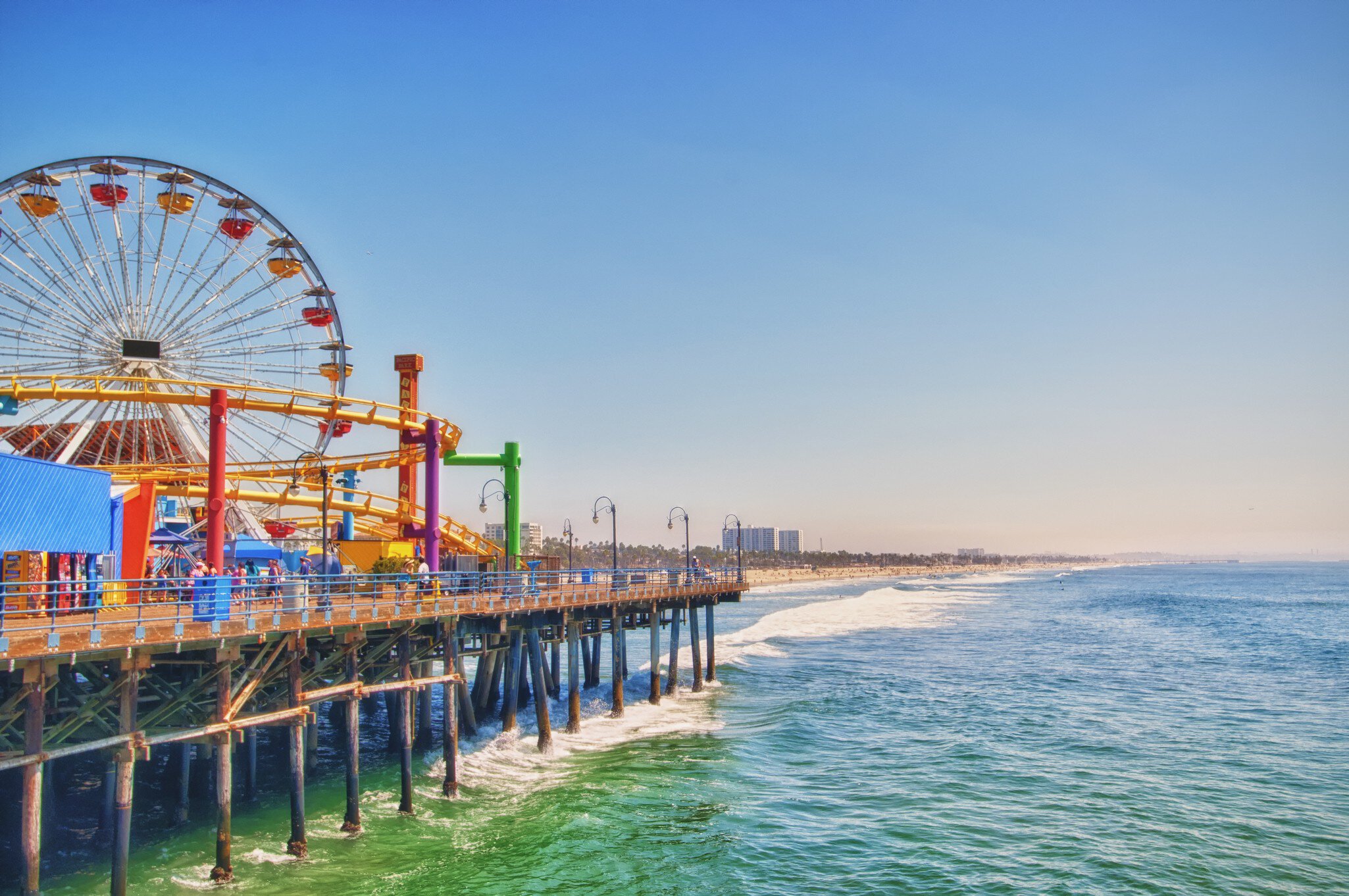 Santa Monica Pier with rides and ferris wheel overlooking ocean.
