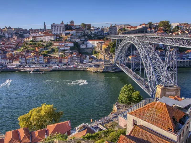 A large bridge spans a river in a hillside city