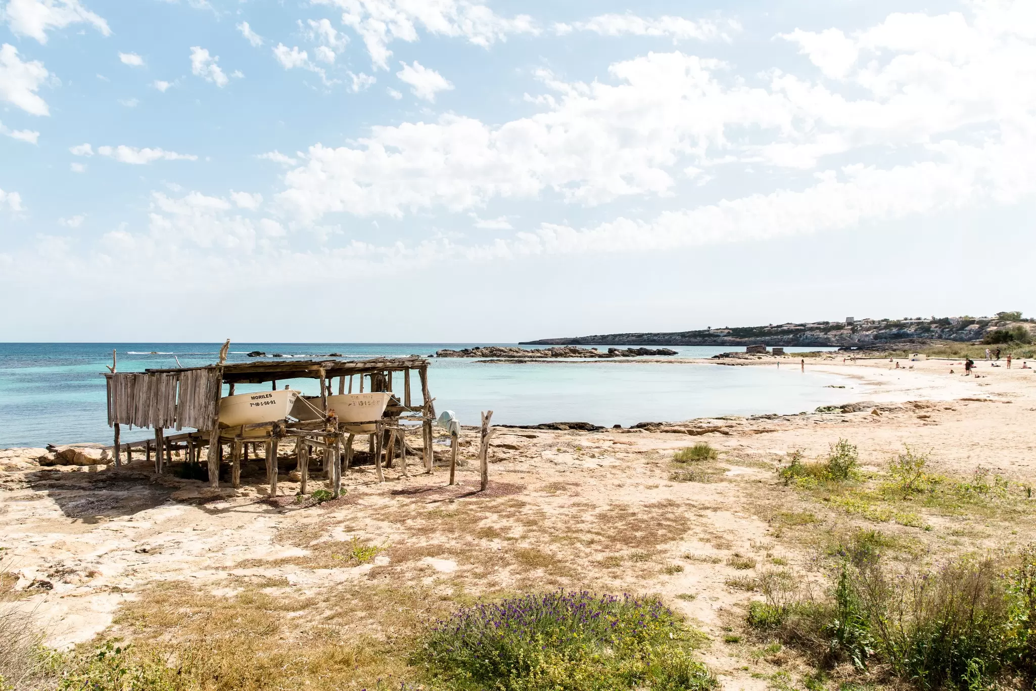 Wooden supports provide a shelter off the sandy beach for small boats on a beach in Formentera, Spain
