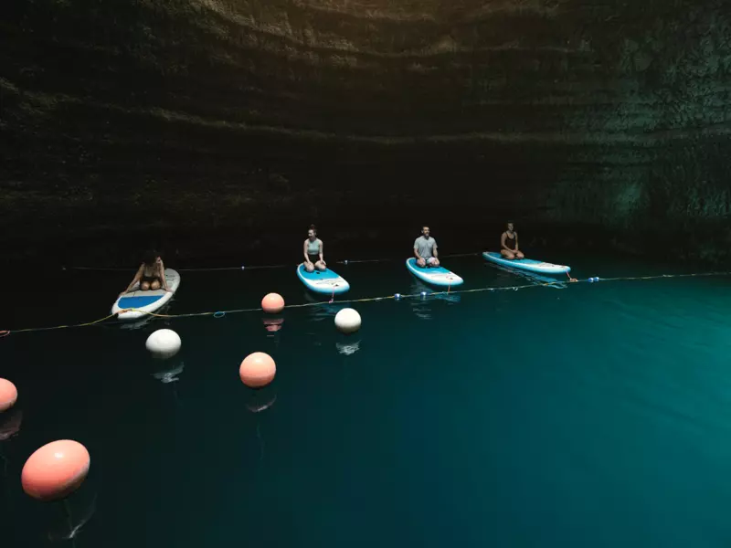 Four people sitting on paddleboards.  