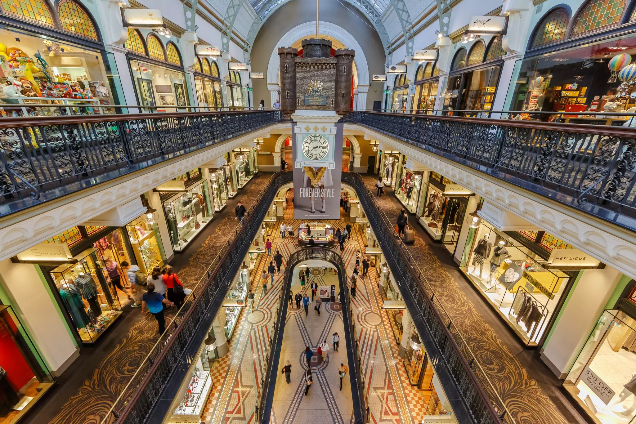 Inside an ornate shopping center, looking down at various levels of stores and shoppers on walkways.