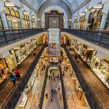 Inside an ornate shopping center, looking down at various levels of stores and shoppers on walkways.