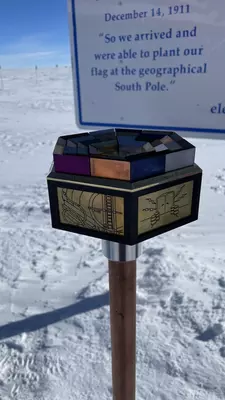 A marker placed in the snow in front of a large sign.