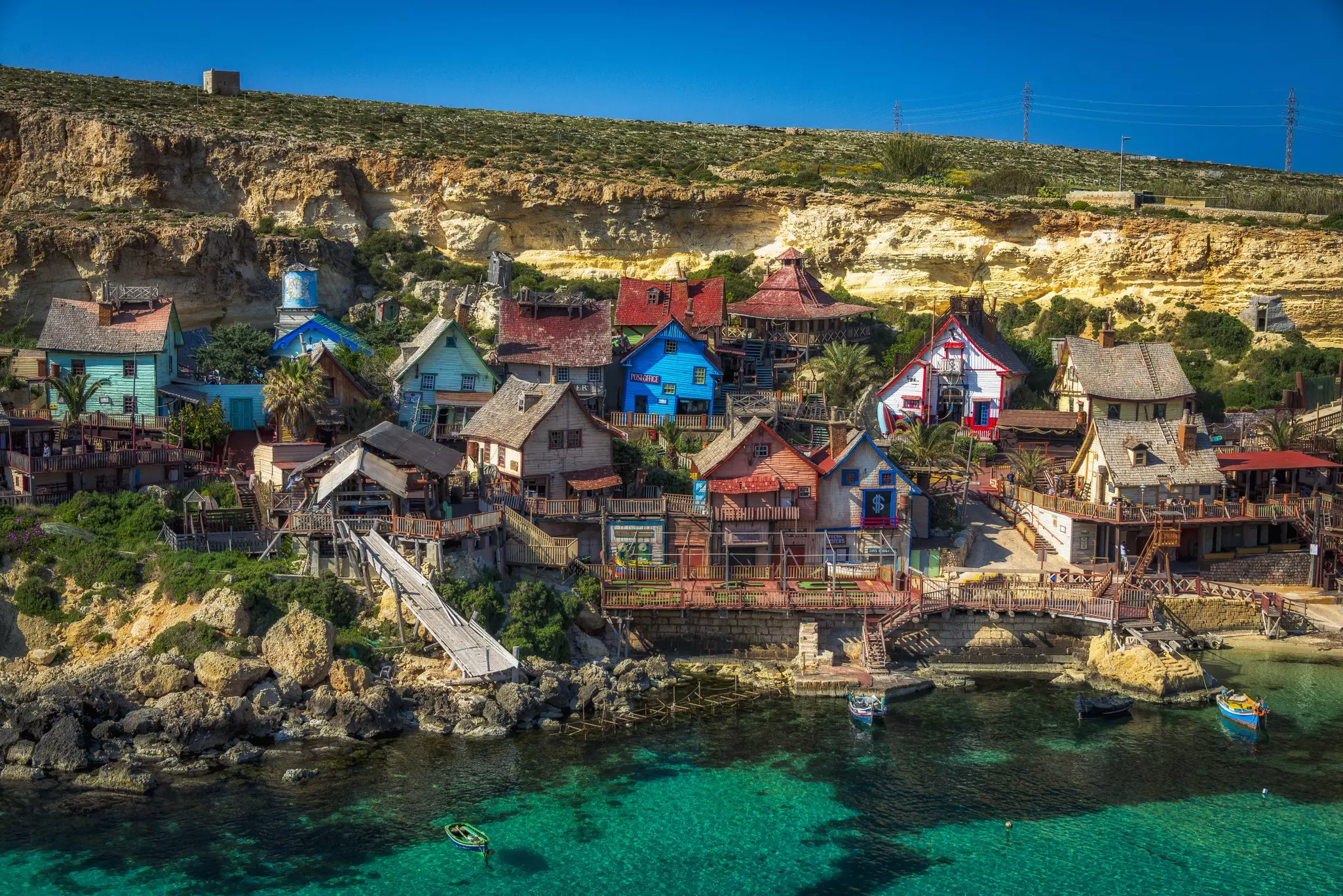 Popeye Village, colorful buildings by a body of clear water.