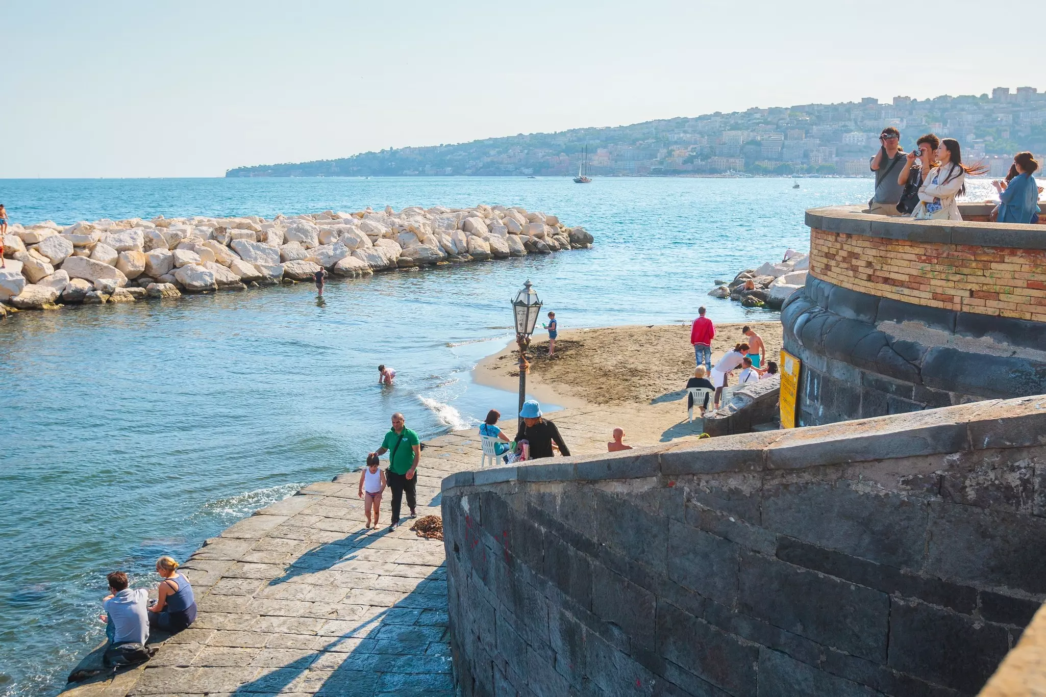 People relax, sunbathe and swim on Mappatella Beach on Quay of Via Francesco Caracciolo., Italy