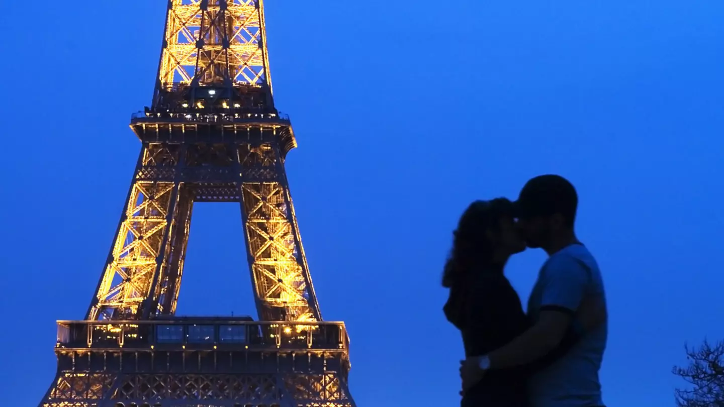A couple embracing in front of the Eiffel Tower at night.