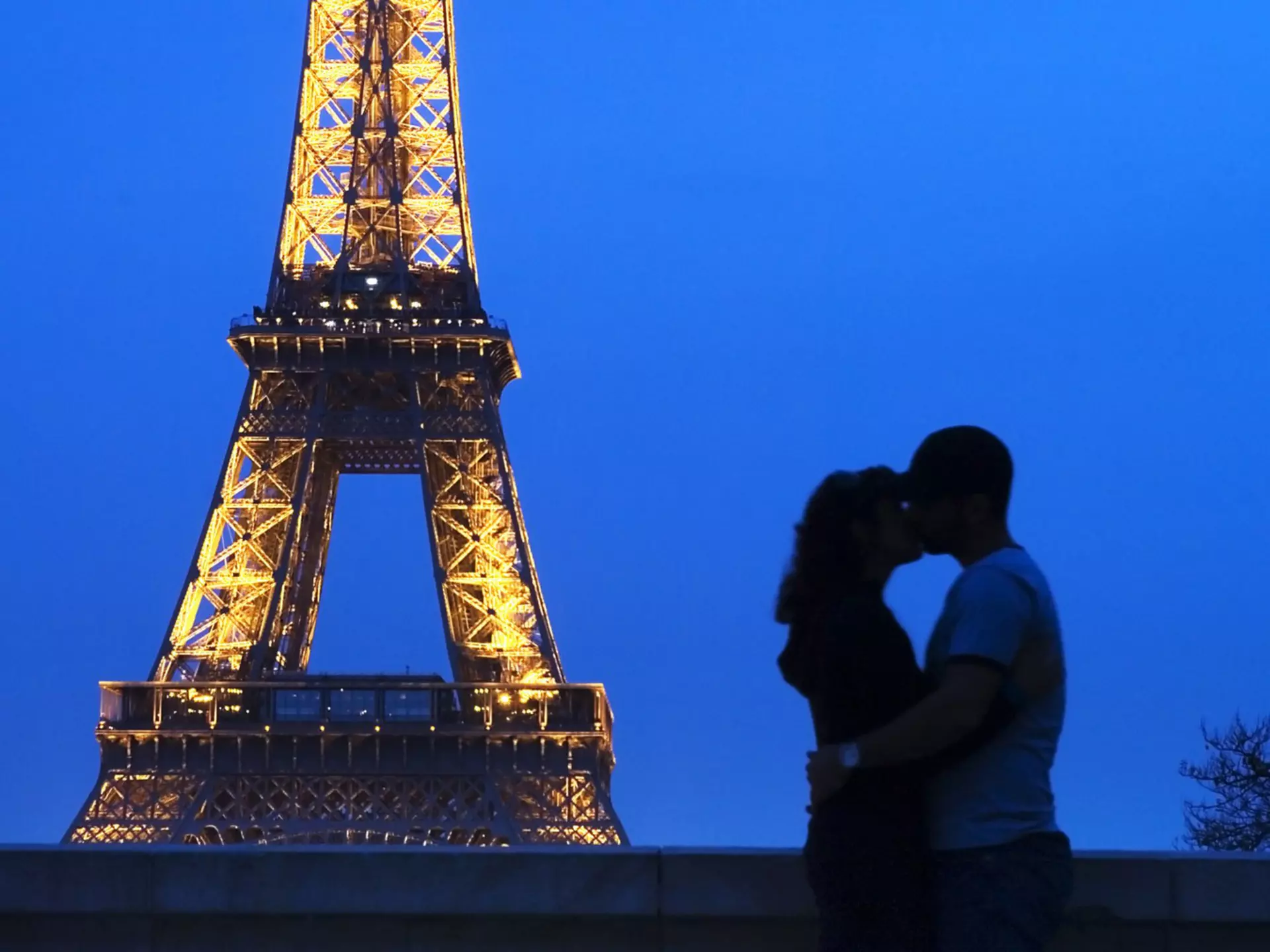 A couple embracing in front of the Eiffel Tower at night.