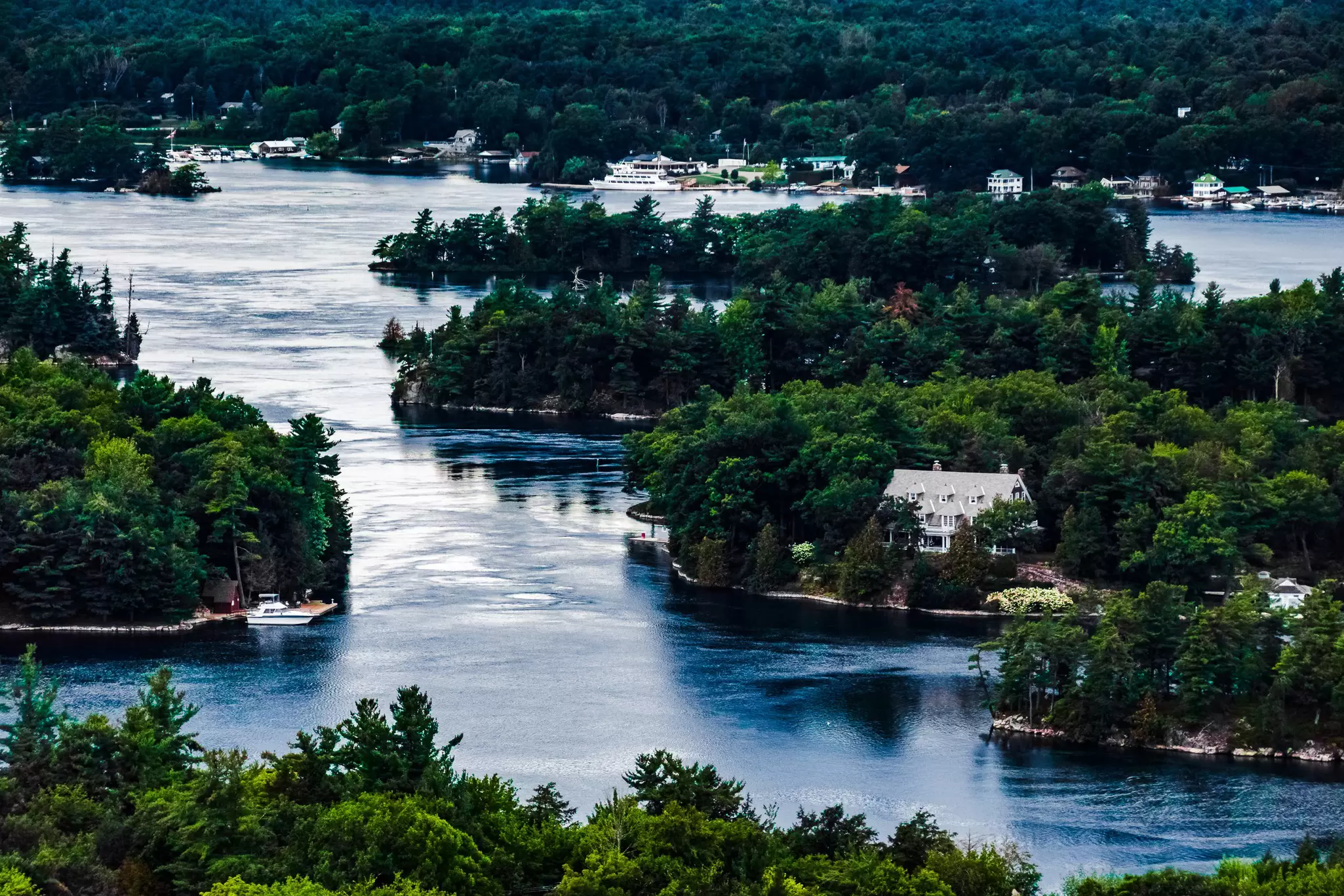 A view of islands covered with dense trees and a mansion, Thousand Islands, Ontario