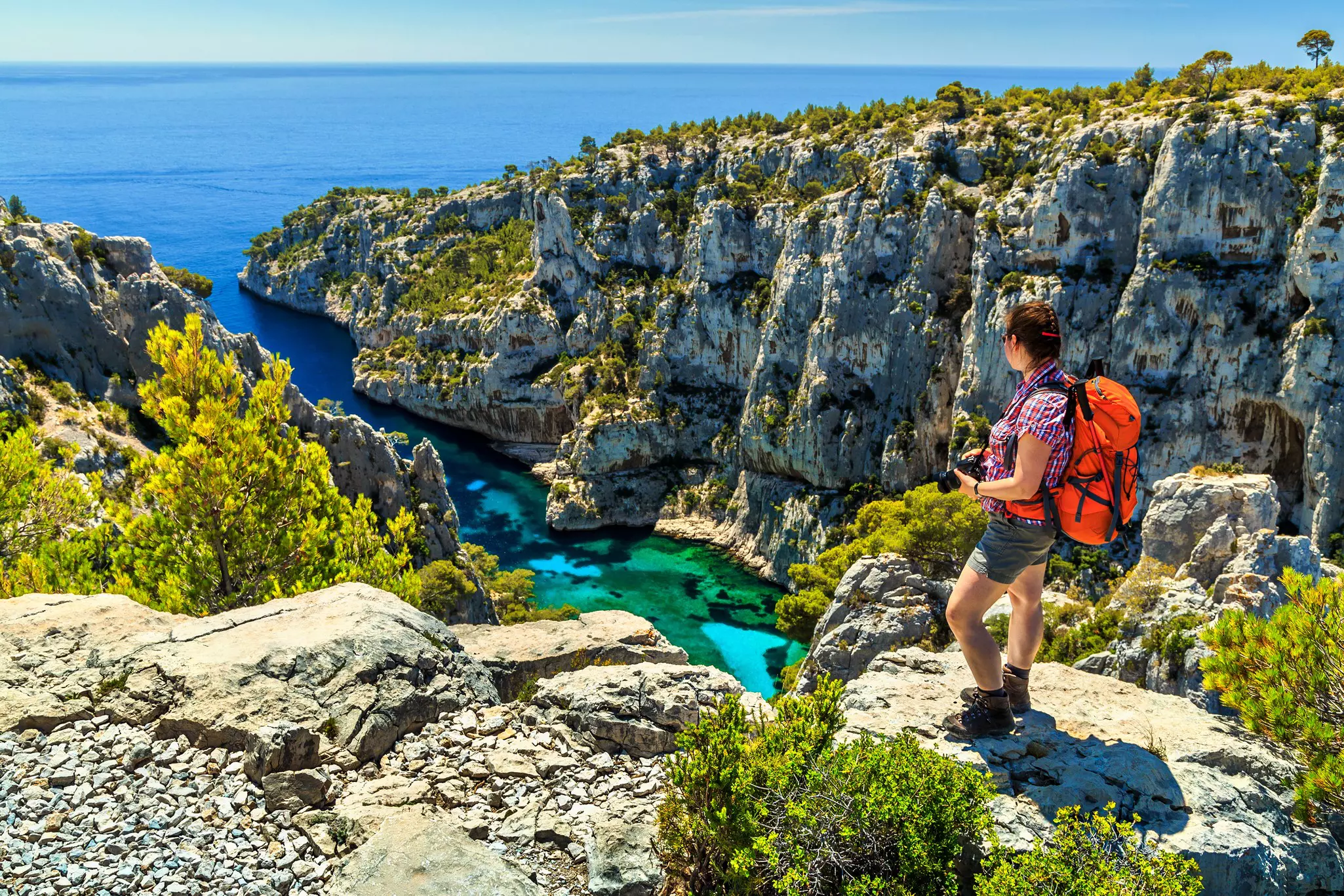 Hiker woman with backpack and camera on the high cliffs, Calanques D'En Vau bay , Calanques National Park, France