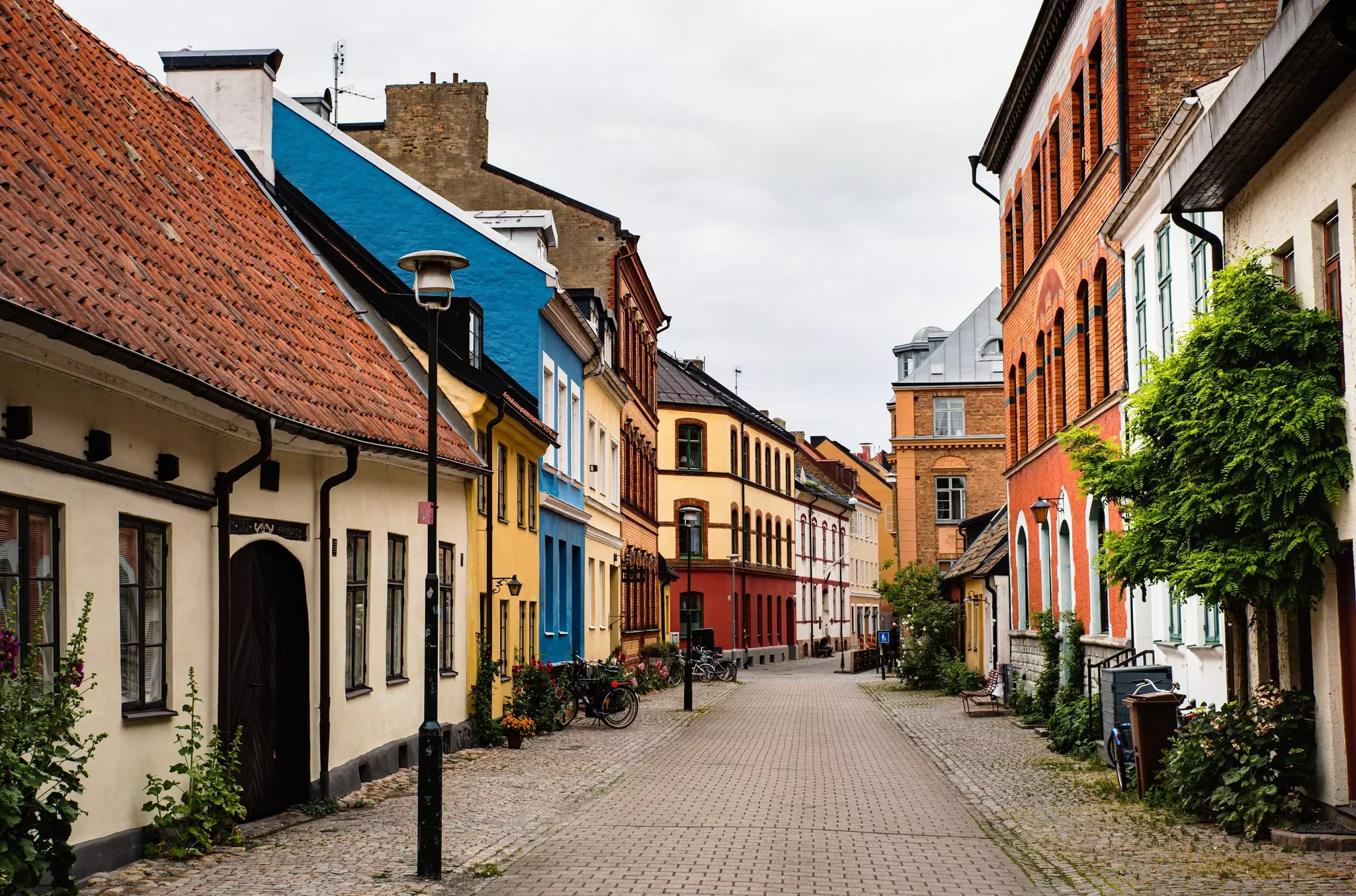 A cobbled street in a city is lined with historic, brightly painted buildings.