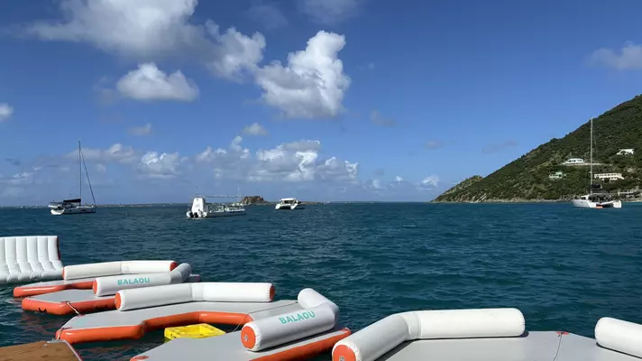 Boats anchored in the ocean near a floating bar 