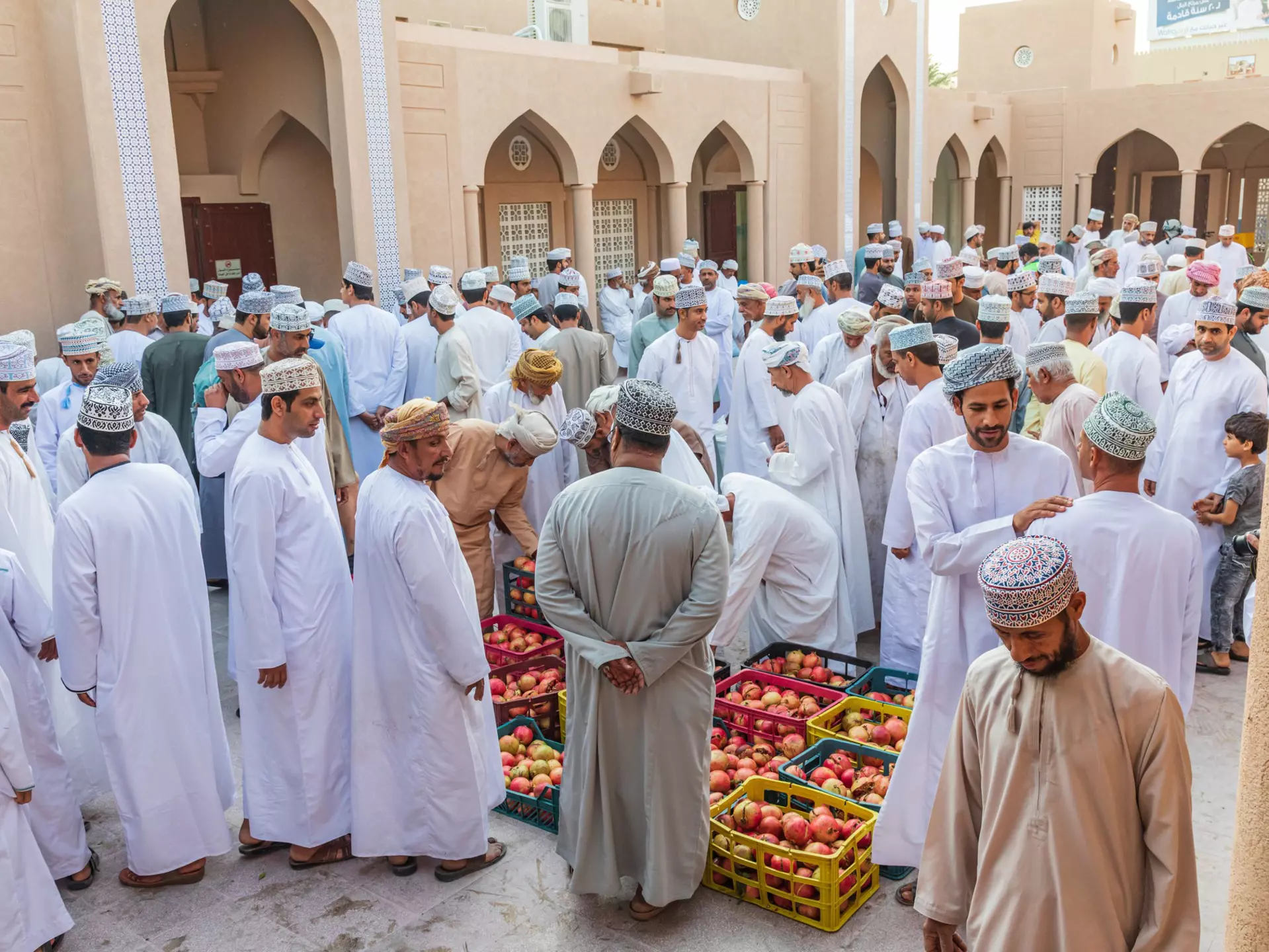 Men haggling over pomegranates at the souk in Nizwa, Oman