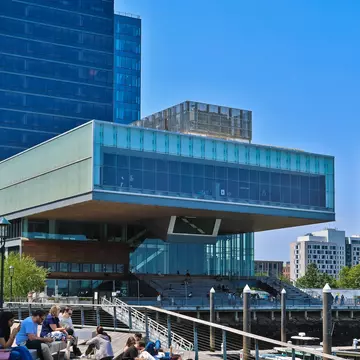 People resting by the water at Pier 4 in Boston Harbor, with the Institute of Contemporary Art in the background in Boston, Massachusetts.