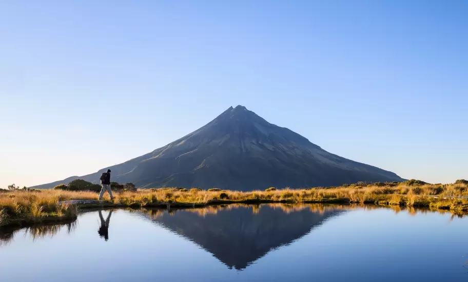 Man hiking the Pouakai circuit. Mt Taranaki under the clear blue sky. New Zealand.