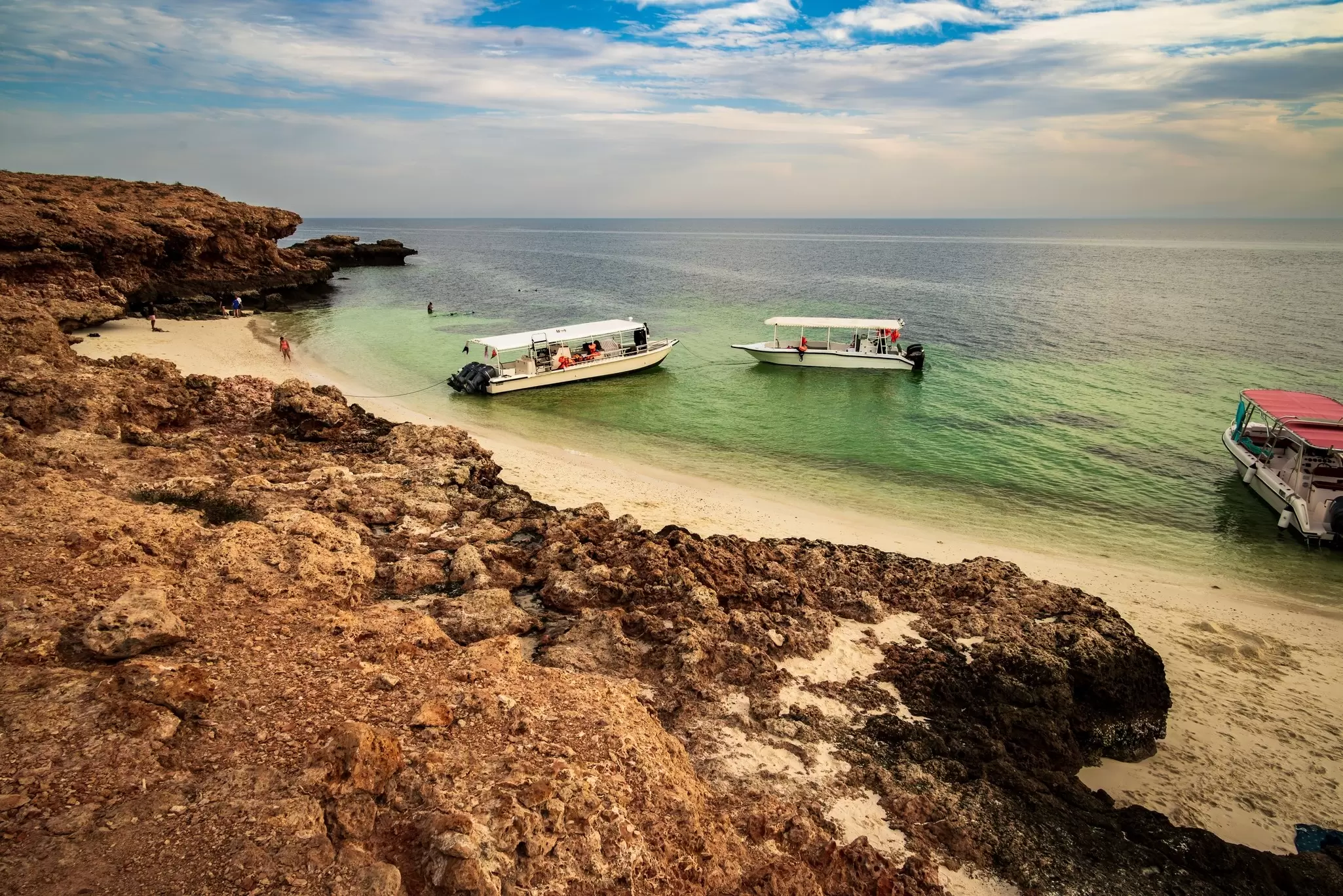 Two tourist boats off the shore of a rocky island: Daymaniyat Islands off the coast of Muscat. 