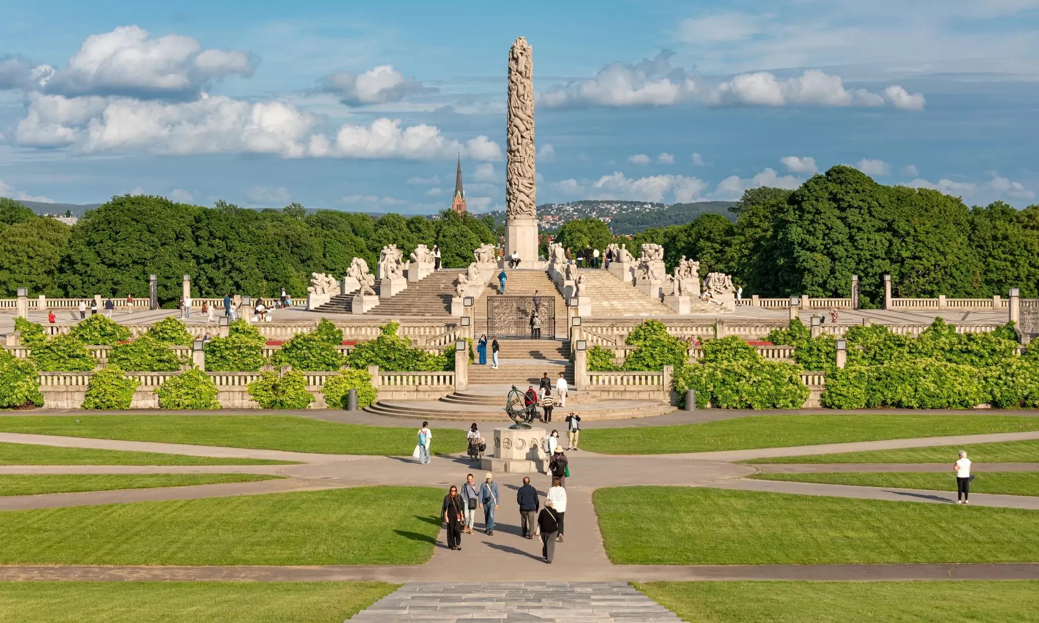 A tall granite column with carved figures in it as the centerpiece in parkland: Vigelandsparken, Oslo