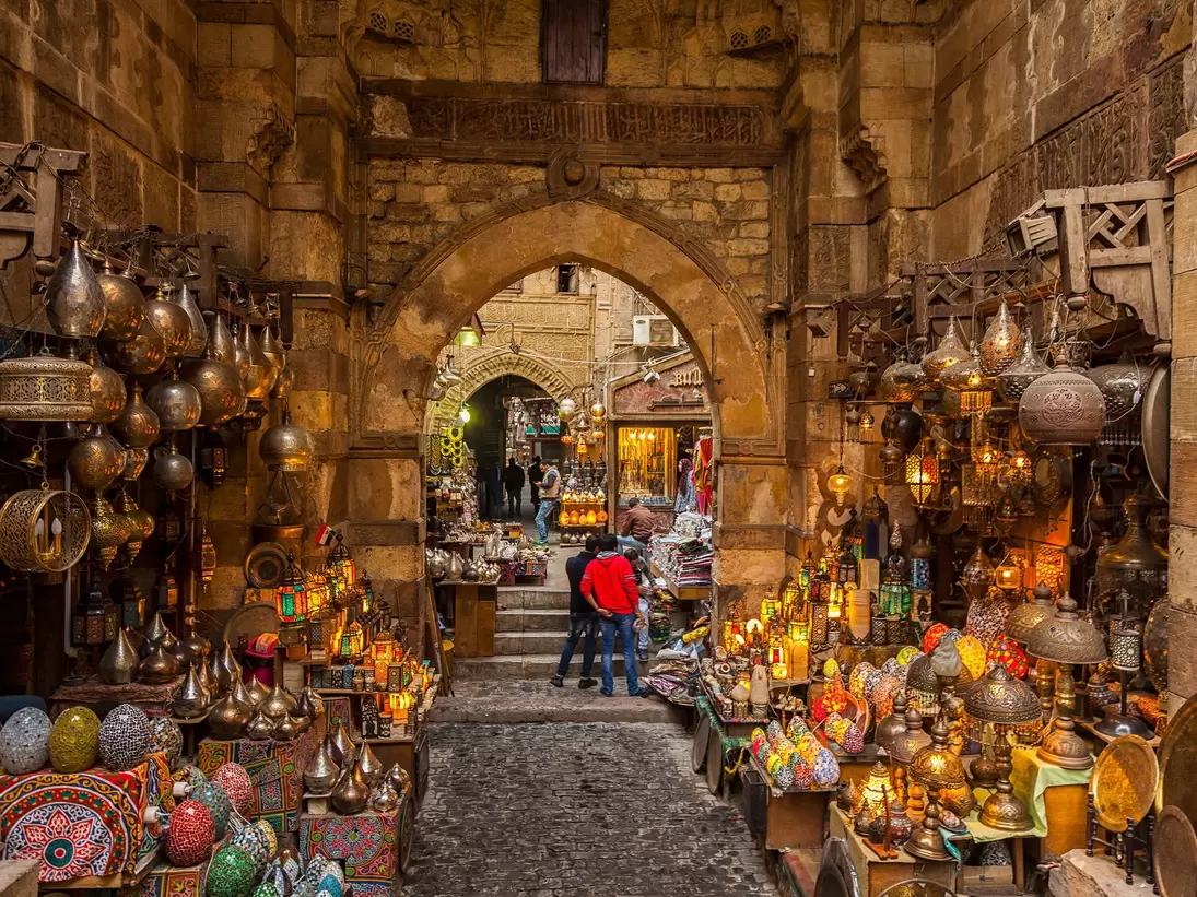 Lamps line the walls on either side of the path through the narrow market alleyway