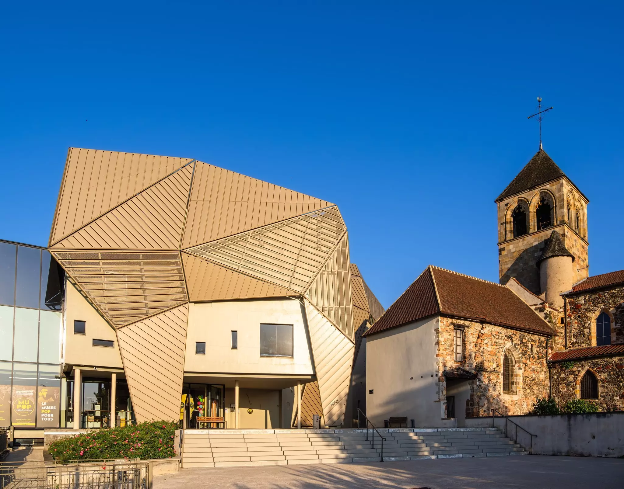 The exterior of the MuPop Music Museum building in Montluçon, France, with a bronze design covering its roof. 