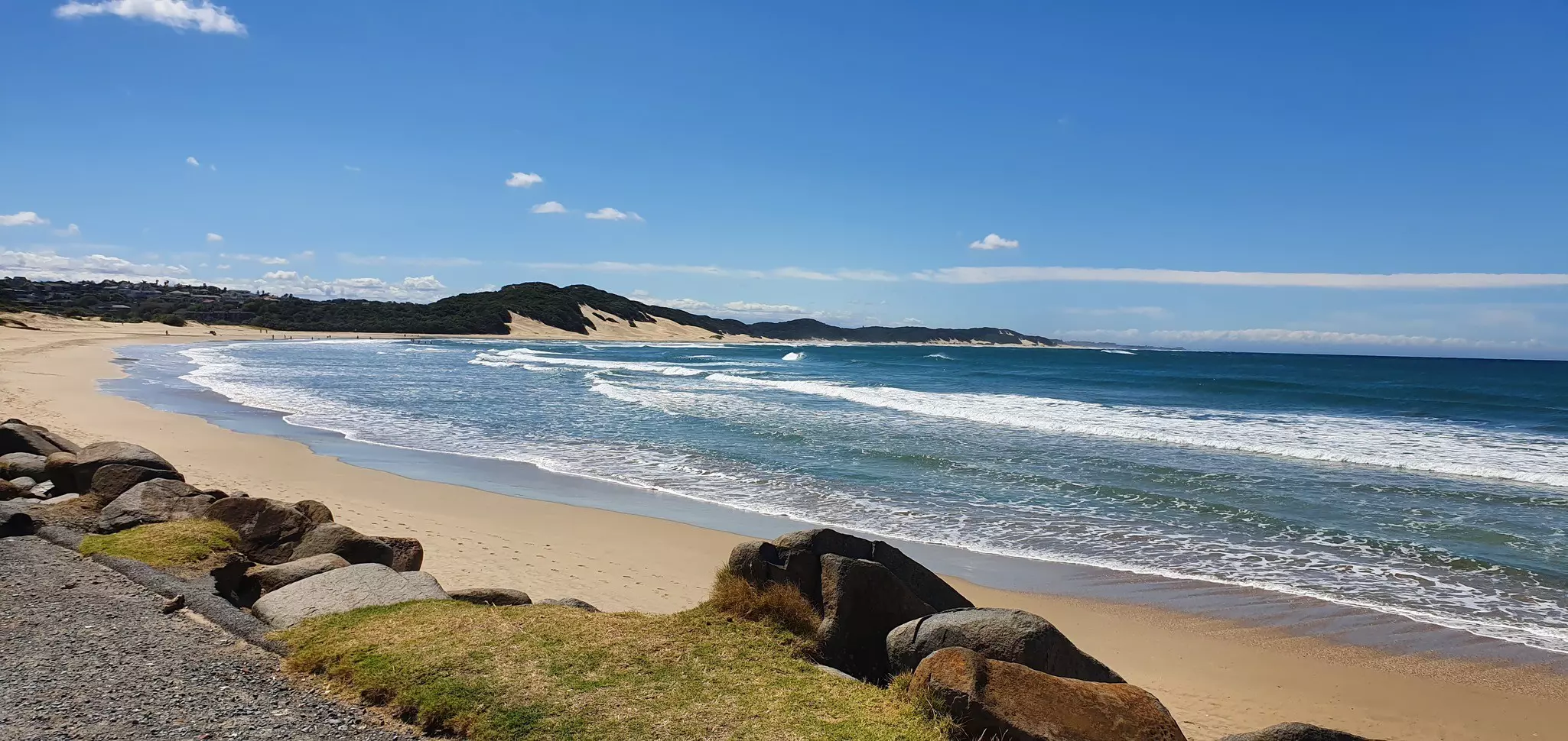 A curve of golden sand lapped by large waves.