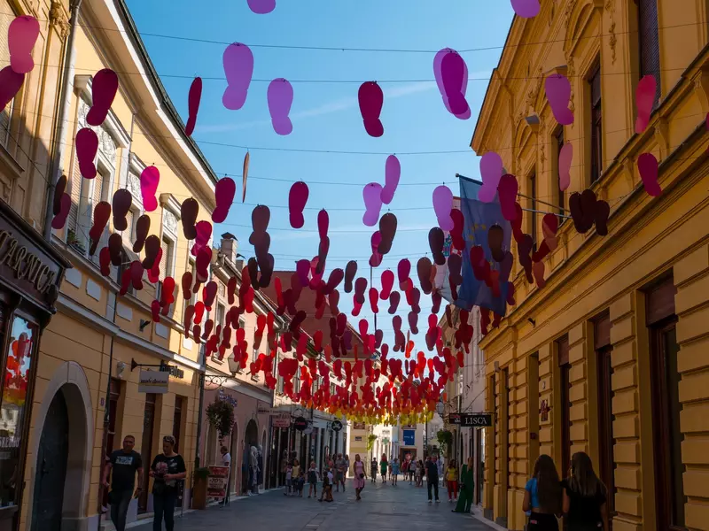 Footstep shapes in purple and red hang from wires strung over a pedestrian street in Varaždin, Croatia.