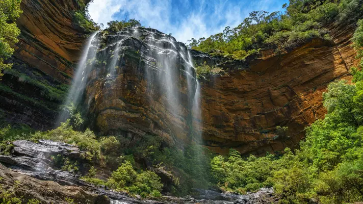 The mist of a waterfall cascading over craggy rocks.