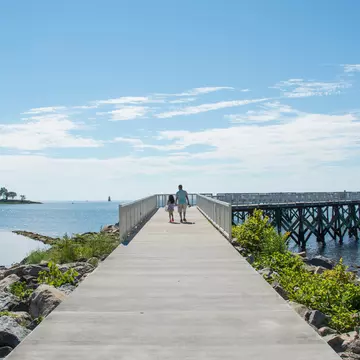 A view down the pier boardwalk on a beautiful summer day by the Long Island Sound at Calf Pasture Beach in Norwalk, Connecticut USA  License Type: media  Download Time: 2021-07-16T00:12:39.000Z  User: AMccarthy_lonelyplanet  Is Editorial: No  purchase_order:   