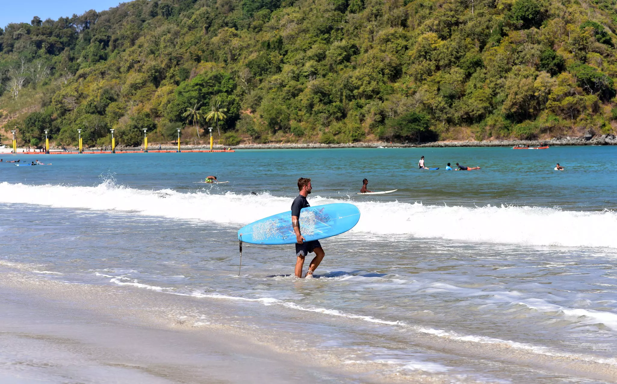 Surfers at the beginners waves of Selong Blanak beach, South Coast, Lombok island, Indonesia