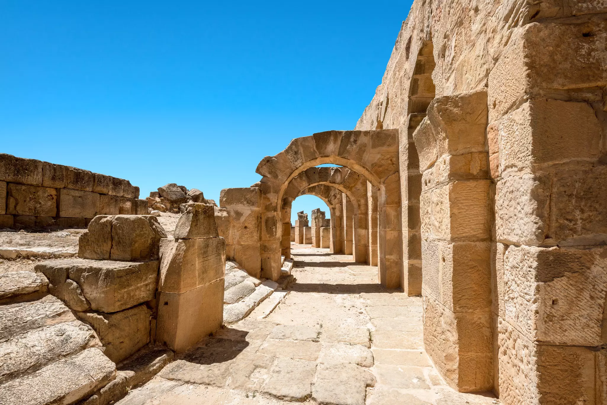 A curved ancient stone walkway with large slabs of stone forming archways.
