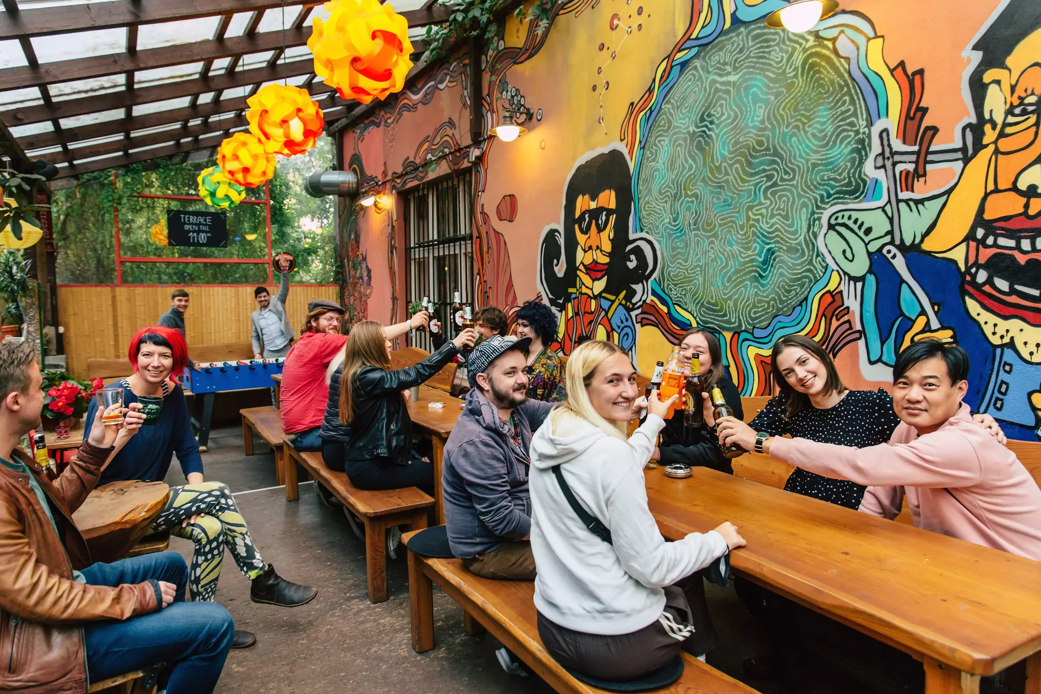 People staying at a hostel cheersing their drinks on an outdoor terrace