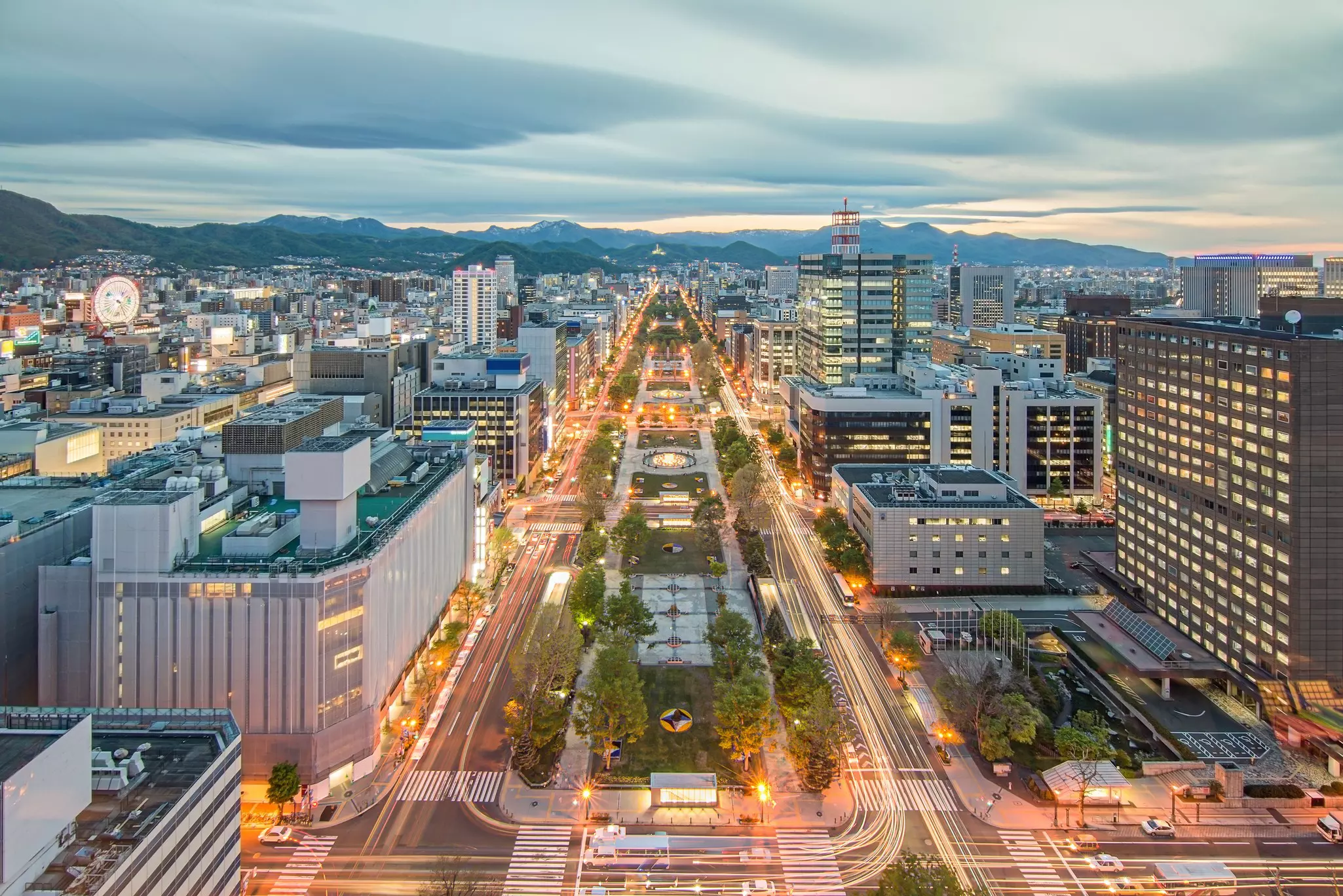 Overhead shot of city streets, with mountains in the distance and clouds above