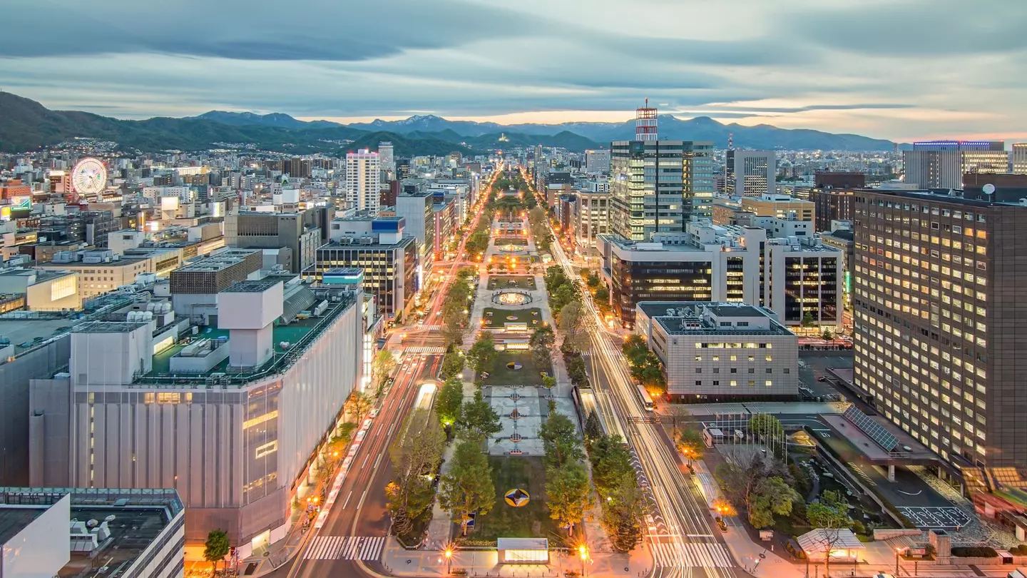 Overhead shot of city streets, with mountains in the distance and clouds above