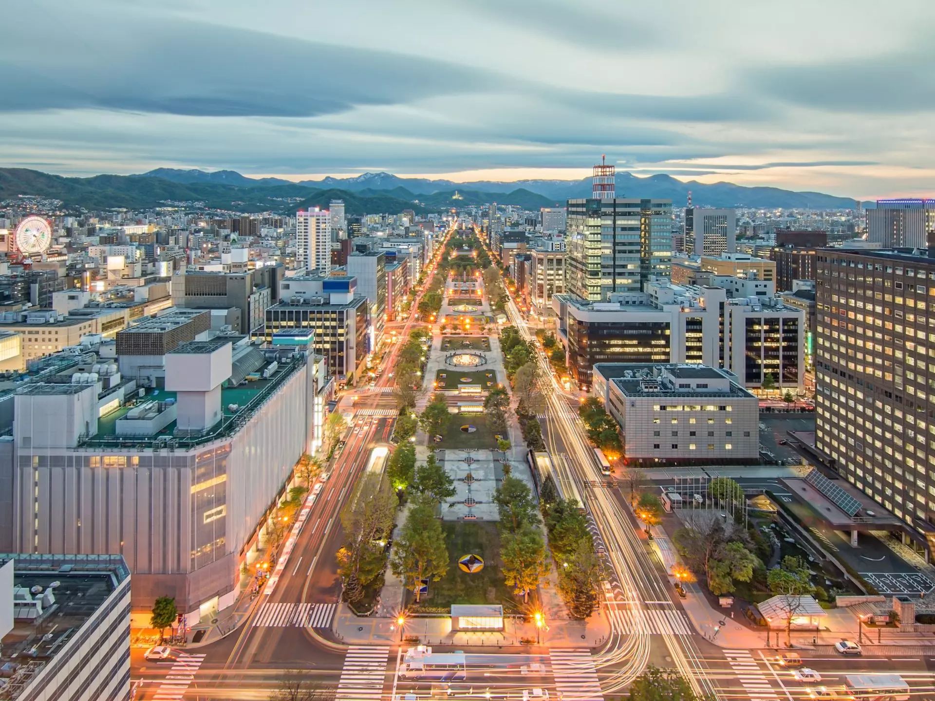 Overhead shot of city streets, with mountains in the distance and clouds above