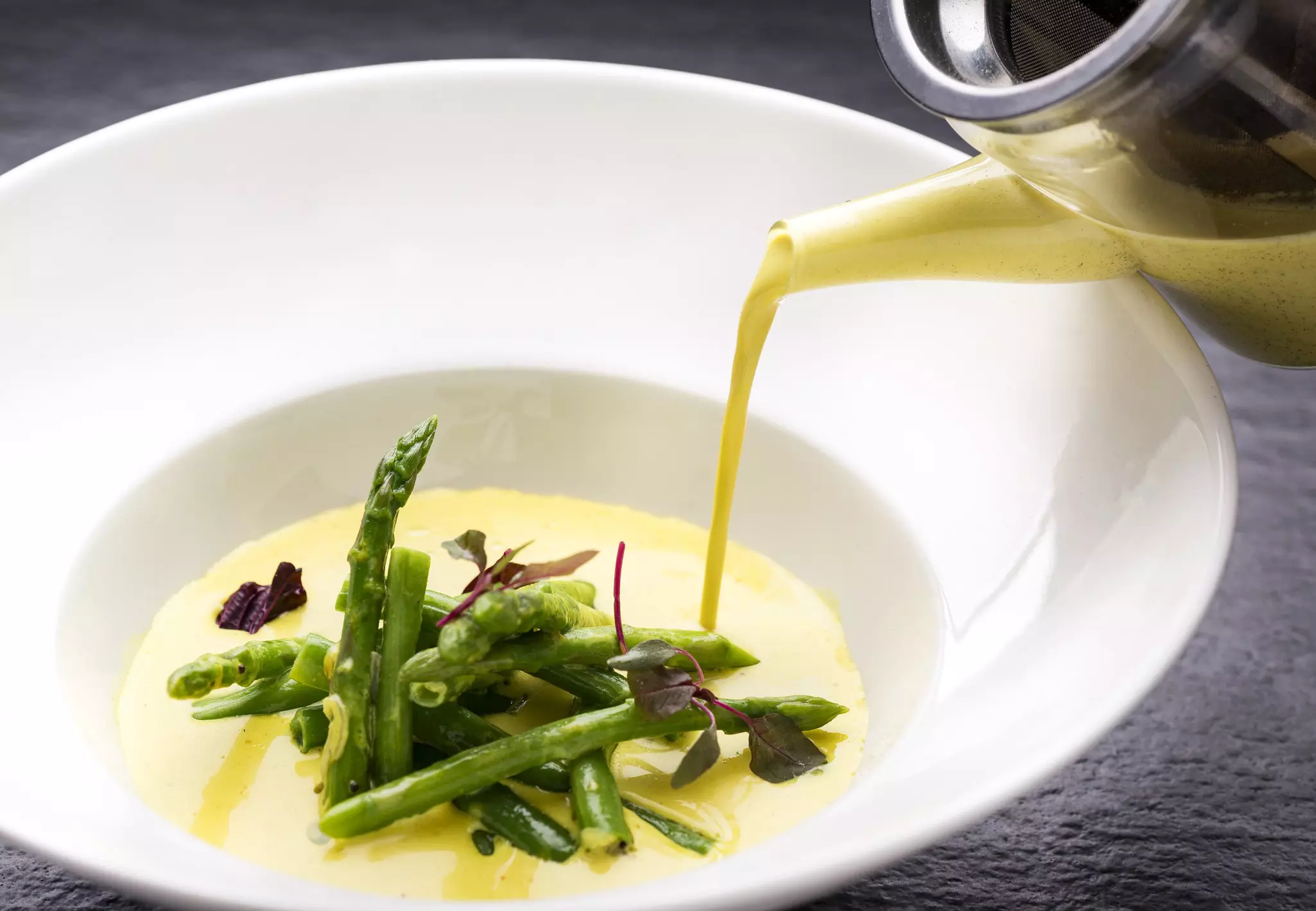Asparagus, French beans and coconut stew being poured from a tea pot