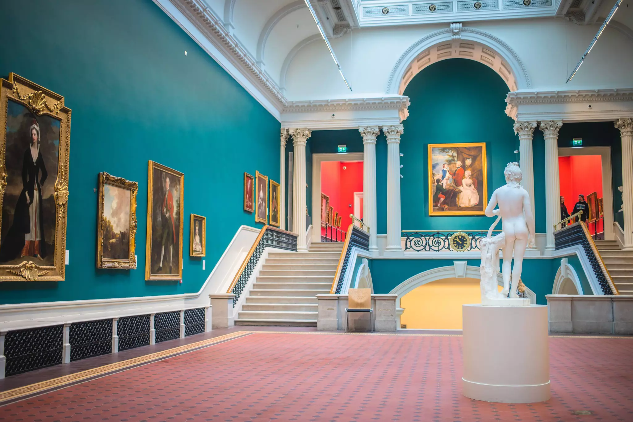Artworks hanging on the walls of a spacious showroom with a white statue in the National Gallery of Ireland.