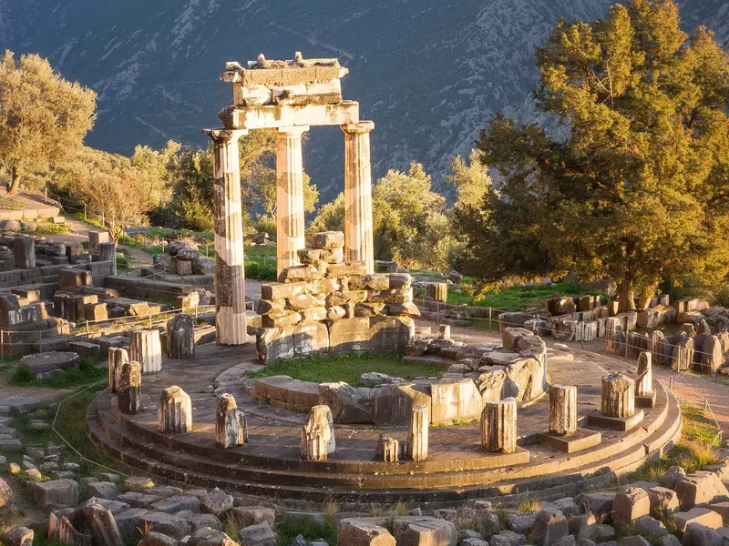 Sunlit ruins with columns in a circle at the Sanctuary of Athena at Delphi, Greece. 