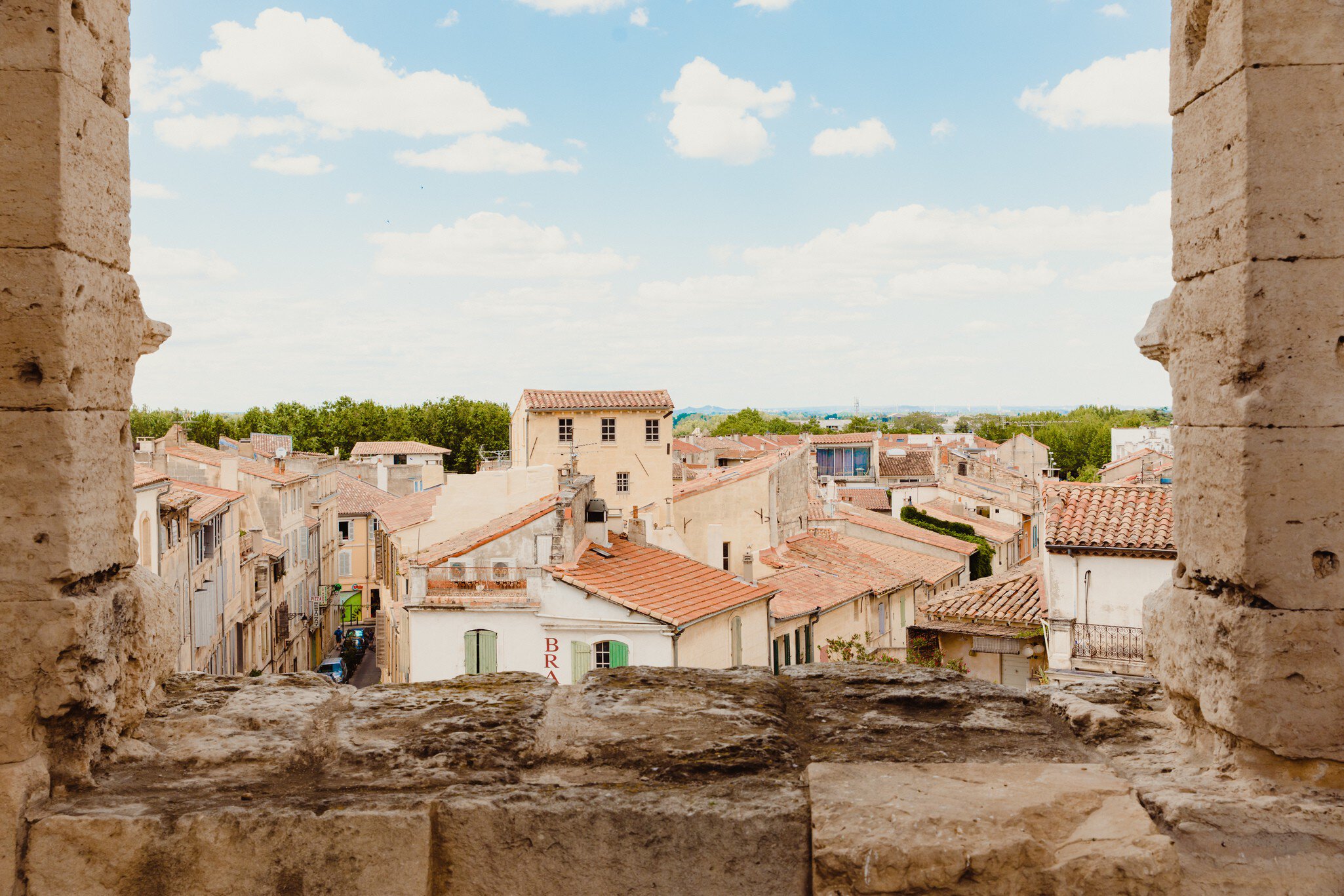 The golden-hued buildings with terracotta roofs, seen through a stone window. 