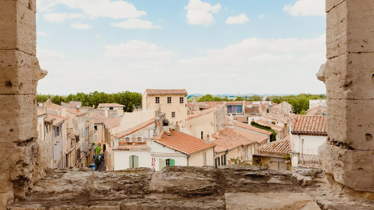 The golden-hued buildings with terracotta roofs, seen through a stone window. 
