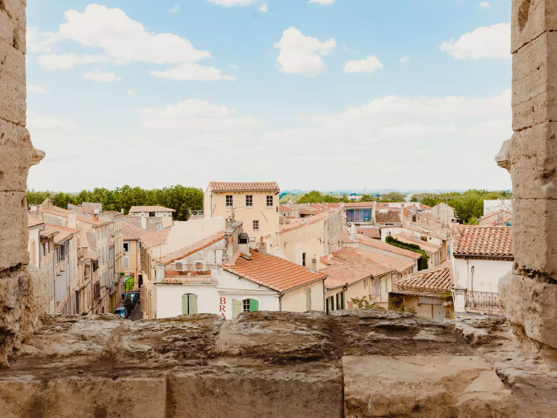 The golden-hued buildings with terracotta roofs, seen through a stone window. 