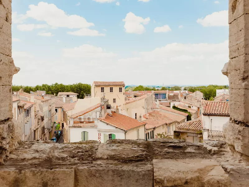 The golden-hued buildings with terracotta roofs, seen through a stone window. 