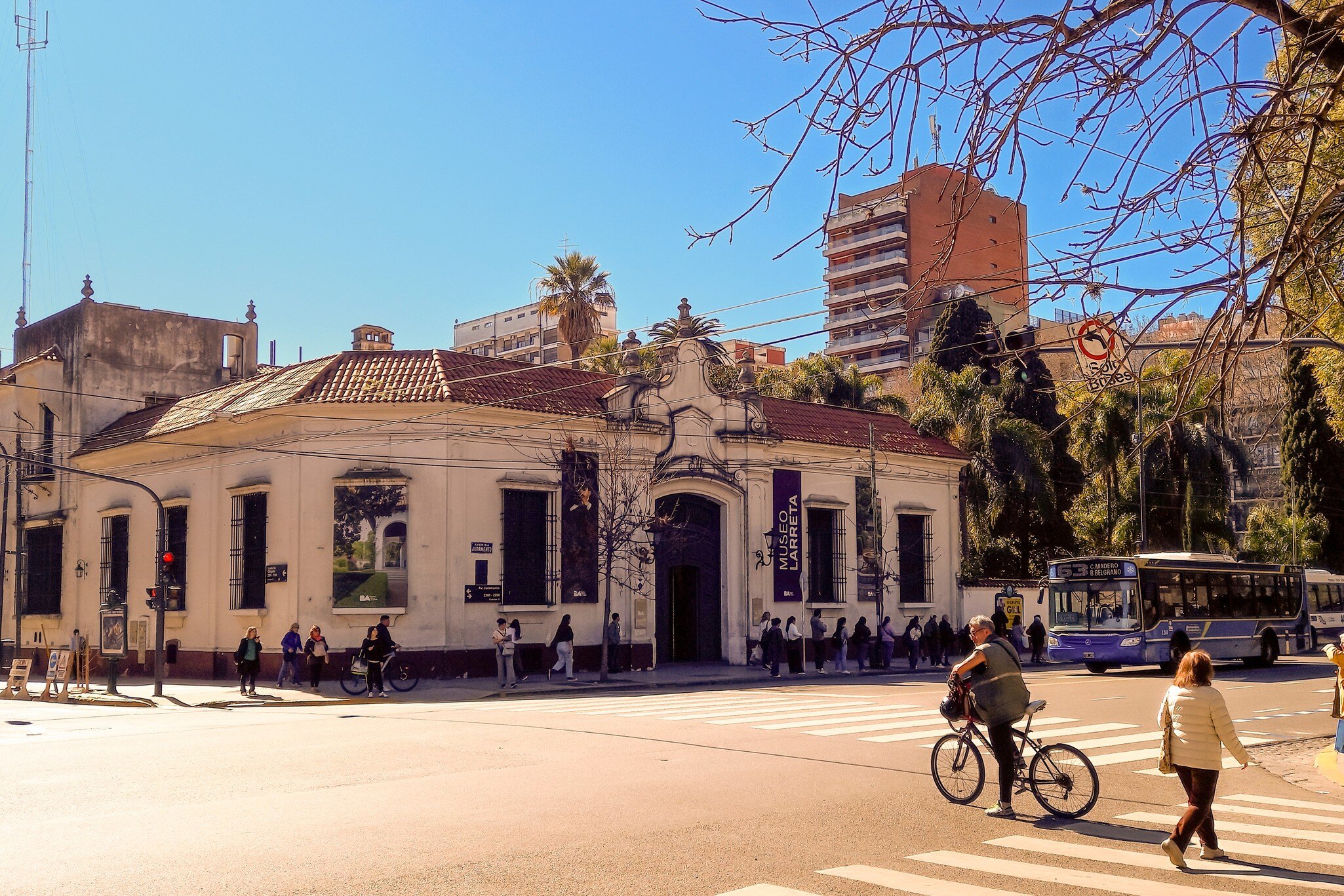 The neocolonial facade of the Larreta Museum of Spanish Art located in Belgrano district, Buenos Aires, Argentina. Biker and woman walking in the foreground.