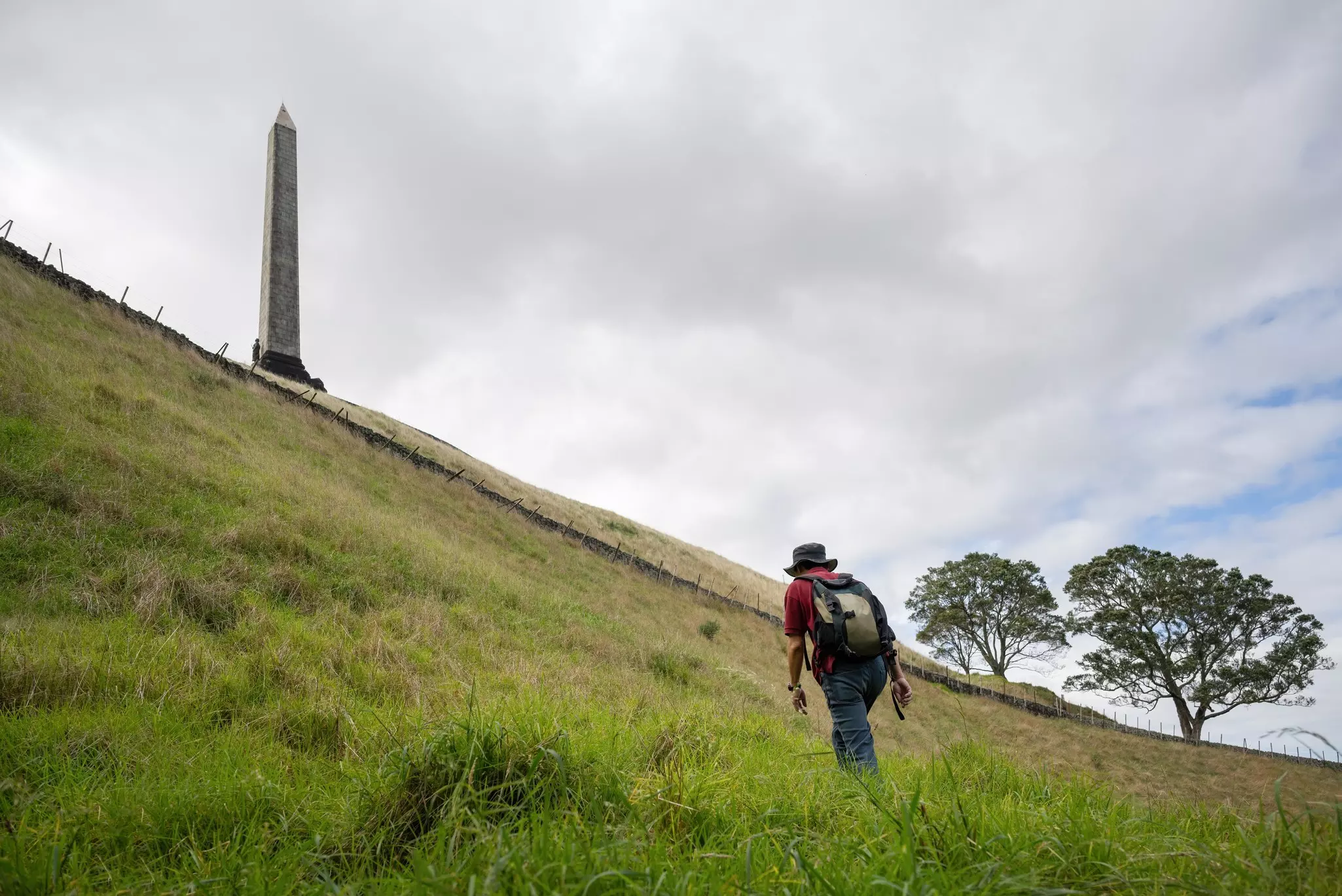 Man walking uphill towards the Obelisk on top of One Tree Hill. Auckland. , License Type: media, Download Time: 2025-02-11T21:07:08.000Z, User: Ppeterson948, Editorial: false, purchase_order: 56530 - Guidebooks, job: Global Publishing WIP, client: Global Publishing WIP, other: Pia Peterson Haggarty